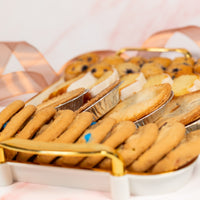 Mini pies and cookies in a glass display case with a pink background