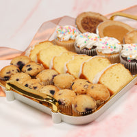 Assorted mini cakes including cupcakes and muffins on a decorative tray.