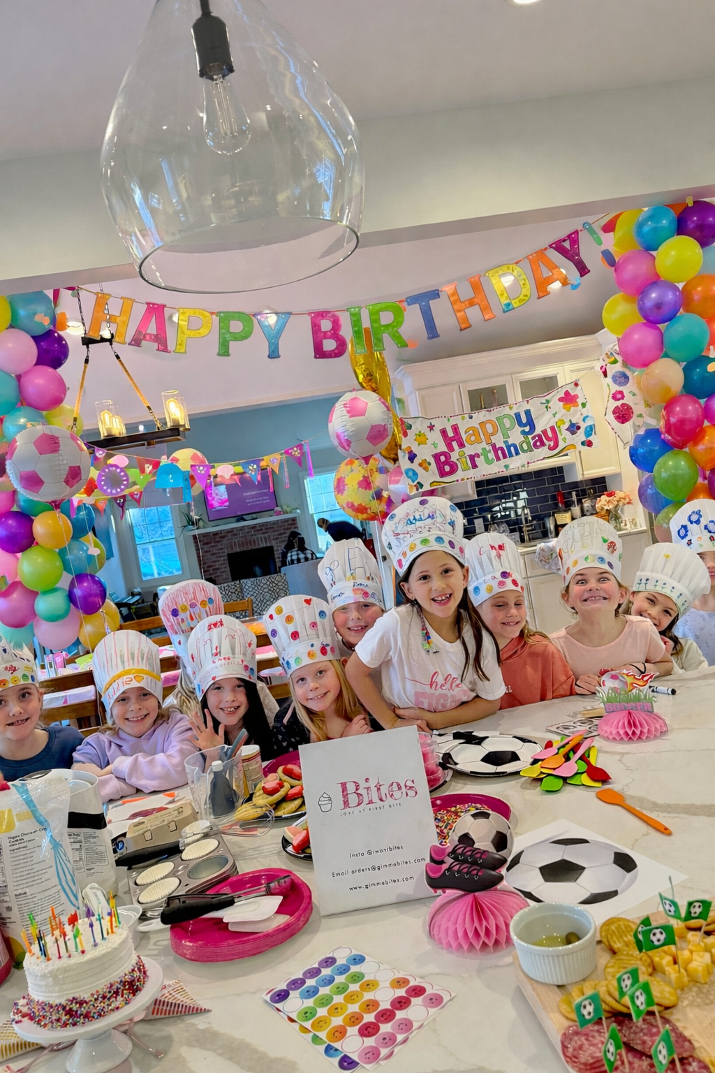 Children wearing chef hats at a birthday party with balloons and decorations.