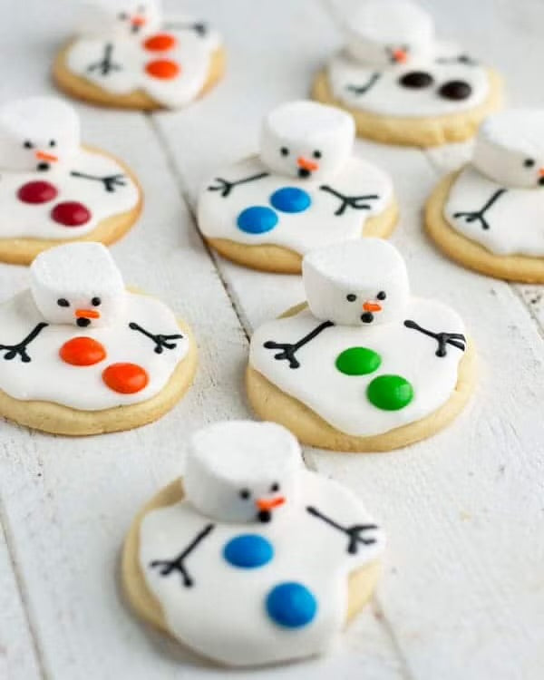Decorative cookies shaped like snowmen on a white wooden surface